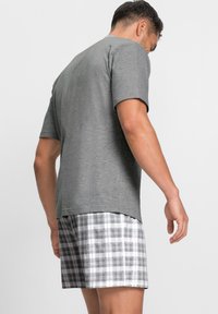 Graues kurzärmliges Baumwoll-T-Shirt kombiniert mit karierter Baumwollshorts in Weiß- und Grautönen, mit entspanntem Schnitt und schlichtem Design.