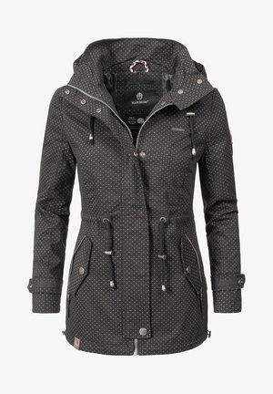 Giacca nera impermeabile con pois bianchi, cappuccio regolabile, cordini in vita, tasche con zip e pattina, e chiusura con bottoni a pressione.