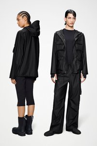 Μαύρο αδιάβροχο μπουφάν με κουκούλα και πολλαπλές τσέπες, συνδυασμένο με μαύρο παντελόνι cargo και αδιάβροχες μπότες. Λεία υφή, λειτουργικός σχεδιασμός.