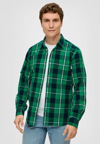 Grünes und marineblaues karriertes Hemd mit Knöpfen, langen Ärmeln und geradem Schnitt. Mit einer Brusttasche und einem weißen Unterhemd. Lässige Baumwollmischung.