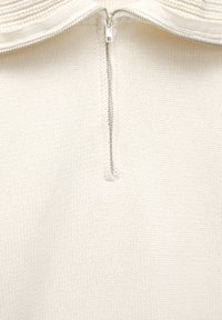 Svijetložuta pletena majica s polu-zip zatvaranjem na ovratniku, s teksturiranim materijalom i minimalno vidljivim šavovima.