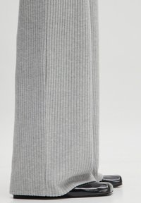 Grey ribbed wide-leg pants with a soft texture, paired with black patent leather flats featuring a square toe design.