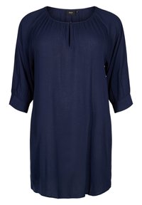 Marinblå tunika med rund halsringning, plisserade detaljer och trekvartslånga ärmar. Lättviktsmaterial med en subtil lyster. Knappar i halsen.