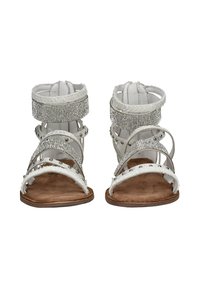 Pair of white flat sandals with rhinestone and silver studded straps, brown footbed, and ankle closure, front view on white background.