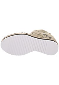 Zapato de ante beige con diseño recortado, suela de goma texturizada blanca y detalle trenzado a lo largo del borde. Construcción plana y ligera.