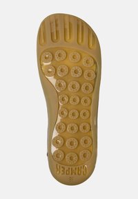 Gummisula på sko, transparent gul med cirkulära mönster för grepp och en strukturerad yta; "CAMPE" märkning synlig. Storlek 38.