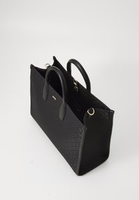 Fekete szintetikus kézitáska strukturált dizájnnal, dupla felső fogantyúval, dombornyomott mintával és arany kiegészítőkkel. Nyitott tetejű, tágas belső térrel.