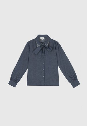Chemise à manches longues bleu marine en tissu léger avec un col à nœud papillon, fermeture à boutons sur le devant et des clous décoratifs le long du bord du col.