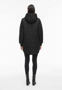 Črna the quilted parka s kapuco, ki ima dolge rokave, rahlo daljši hrbet in strukturiran diamantni vzorec po celotni tkanini.