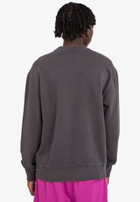 Grauer Oversized-Pullover mit rundem Halsausschnitt und gerippten Bündchen, der eine weiche Textur und eine lässige Passform hat, kombiniert mit pinken Shorts.