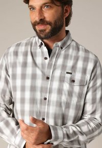 Grijs en wit geruit overhemd met lange mouwen, voorzien van een button-down kraag, een borstzakje en bruine knopen met een zachte katoenen textuur.