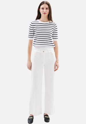 Pantalons larges blancs avec des accents de boutons dorés, associés à un haut à rayures bleu marine et blanche à manches courtes. Textures lisses, design moderne et décontracté.