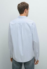 Witte button-up shirt met blauwe verticale strepen, lange mouwen, een standaard kraag en een afgeronde zoom. Katoenen materiaal met een gladde textuur.