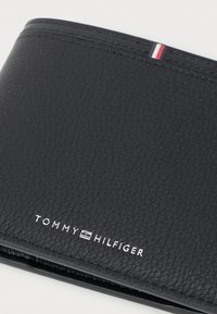 Black leather wallet with a textured surface, featuring white brand logo and a red, white, and blue accent stripe along the top edge.