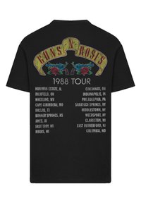 Black cotton t-shirt featuring "GUNS N' ROSES" in yellow above two roses and a revolver, with "1988 TOUR" and city list in white text below.