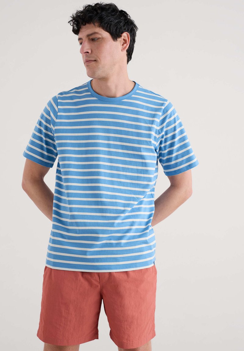 Kortärmad T-shirt i ljusblått med vita horisontella ränder. Rundhals. Matchad med korallfärgade shorts. Mjuk, bomullsmaterial.
