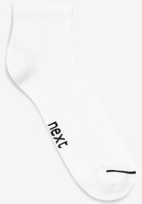 Valkoinen nilkkasukka ribbaamalla verkkokohdalla, jossa on musta "next" -logo ja musta raita varpaassa. Valmistettu pehmeästä, joustavasta materiaalista.