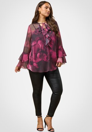 Ohut, kevyt violetti paita kukkakuviolla, röyhelökauluksella ja kellotetuilla hihoilla, yhdistettynä mustiin istuviin housuihin ja remmilettikorkokenkiin.