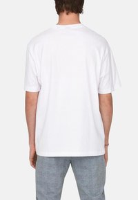 Weißes Baumwoll-T-Shirt mit lockerer Passform, kurzen Ärmeln und rundem Ausschnitt. Glatte Textur und schlichtes Design, ohne sichtbare Grafiken oder Muster.