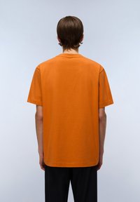 Orange bomulds T-shirt med afslappet pasform, korte ærmer og lige kant. Bagfra ses en glat tekstur og et simpelt design.