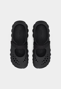 Paire de Crocs noires à bout fermé avec des trous de ventilation et des sangles réglables, vue de dessus sur un fond blanc uni.