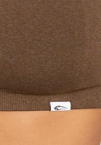 Sostenitore sportivo marrone a coste con un design aderente e un'etichetta in tessuto bianco che presenta un logo nero sul bordo inferiore.