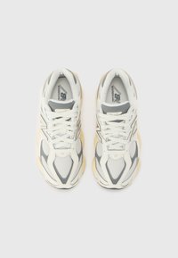 Sneaker sportive con tomaia in rete e sintetico bianchi e grigi, con suola voluminosa color crema e dettagli di cucitura tonale.
