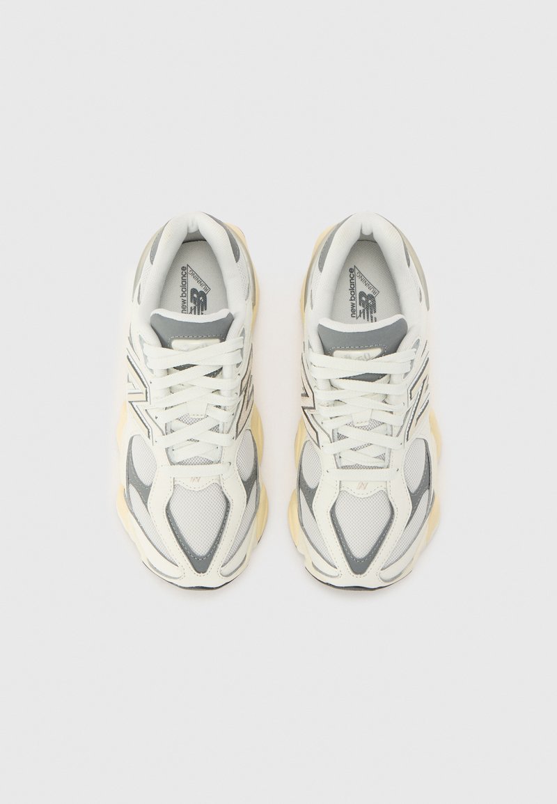 Sneaker sportive con tomaia in rete e sintetico bianchi e grigi, con suola voluminosa color crema e dettagli di cucitura tonale.