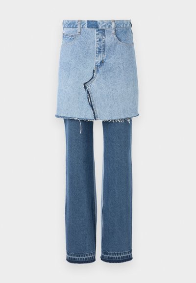 Džinsinė apranga, sudaranti šviesiai mėlyną mini sijoną viršuje ir tamsiai mėlynus platėjančius džinsus apačioje; turi nusidėvėjusią kraštą ir klasikę džinsinės tekstūros.