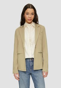 Khaki blazer gemaakt van zachte stof met een getailleerde pasvorm, voorzien van twee voorkruiszakken en een enkele knoopsluiting, gedragen over een crèmewitte gestreepte shirt.