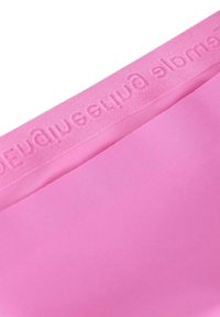 Rosa sportbh med en slät yta och pr präglad logotyp längs bandet. Har en sömlös design och en böjd halsringning.