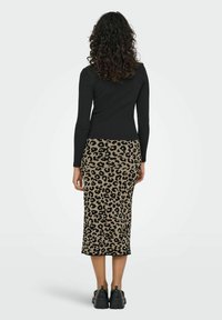 Haut à manches longues noir associé à une jupe crayon à imprimé léopard de longueur mi-genou. La jupe présente un tissu lisse et texturé avec une silhouette ajustée.
