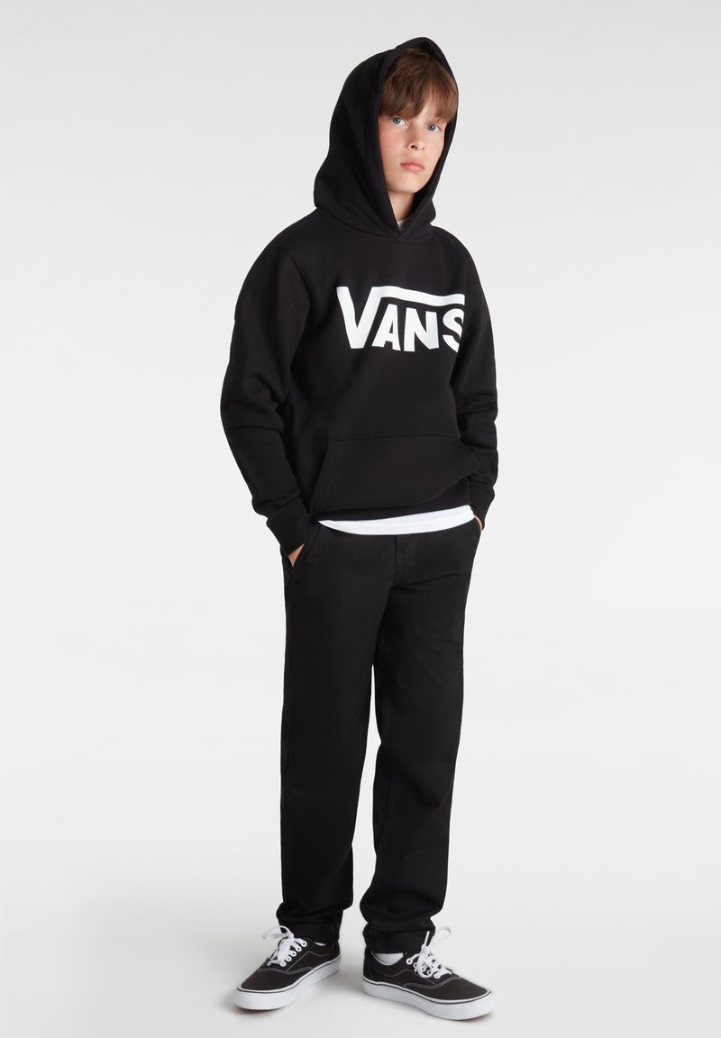 Hoodie noir avec un logo "VANS" blanc, poche avant et capuche avec cordon de serrage, associé à un pantalon noir et des baskets noires avec des semelles blanches.