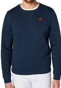 Granatowy sweter z ribbowanym wzorem, okrągły dekolt, z czerwonym logo na piersi oraz ribbowanymi mankietami i dołem.