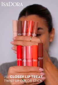 Nine twist-up lip color sticks in various shades, including pink, peach, and brown, displayed in a hand, showcasing smooth cylindrical design.