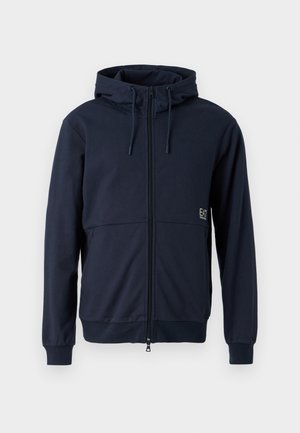 Felpa con zip di colore blu navy, con cappuccio regolabile, tasche anteriori e polsini elasticizzati. Tessuto morbido e logo ricamato sul lato sinistro.