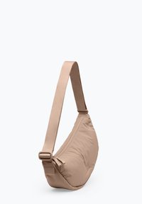 Sac d'épaule beige en forme de croissant avec bandoulière ajustable et fermeture éclair, fabriqué en tissu rembourré.