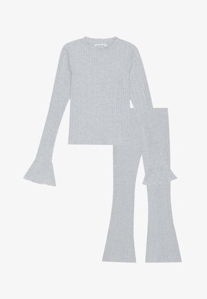 Sada šedého žebrovaného pleteného topu a kalhot s dlouhými rukávy a rozšířenými manžetami a přiléhavými rozšířenými nohavicemi, vyrobená z měkké látky.