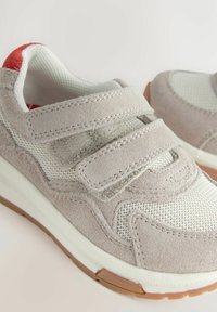 Grå mocka- och mesh-sneakers med vita accenter, som har dubbla kardborreband, strukturerade ytor och en gummisula i brun färg.
