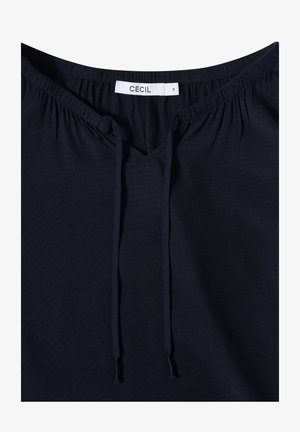 Marineblå bluse med V-hals, elastisk samling ved halsudskæringen og justerbare snore til pasform. Lavet af blødt, let stof.