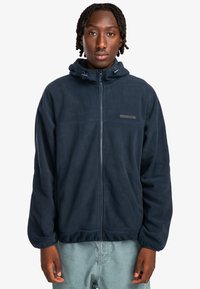 Marinefarvet fleece zip-jakke med hætte, har en glat tekstur, frontziplukning og diskret logo-detail på brystet.