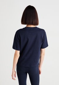 T-shirt blu navy a maniche corte con scollatura rotonda e vestibilità rilassata. Tessuto di cotone liscio, senza motivi o dettagli visibili.