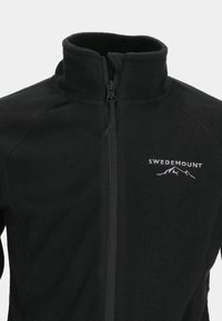 Musta fleece-takki, jossa on vetska edessä, korkea kaulus ja valkoinen "SWEDEMOUNT" -logo, jossa on vuoristografiikka vasemmassa rinnassa.