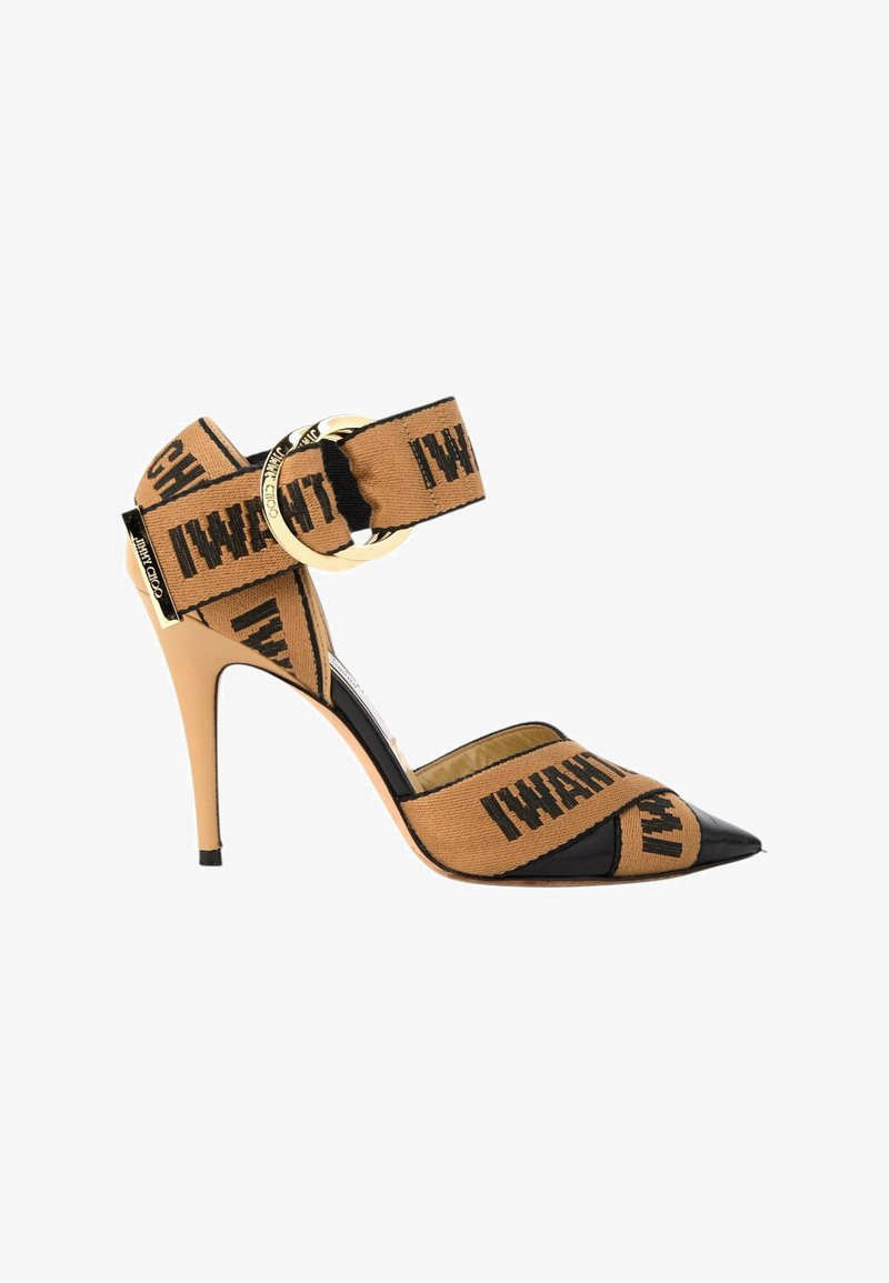 Sandale à talons hauts pour femme avec des brides en tissu beige marquées d'un texte noir et une boucle dorée, avec une pointe noire effilée.