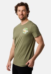 Olivenfarvet bomulds T-shirt med rund hals, med et farverigt grafisk print på brystet og korte ærmer. Glat tekstur.