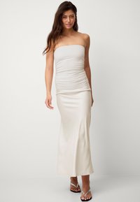Strapless, hellbeiges Maxikleid aus glattem, elastischem Stoff mit gerafften Details an der Taille und einer eleganten, figurbetonten Silhouette.