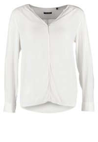 Blouse blanche à manches longues en tissu lisse avec un col en V, un pli à l'avant et un ourlet légèrement arrondi. Dotée d'une fermeture à boutons.