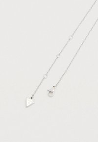 Ασημένιο κολιέ με αλυσίδα που διαθέτει μενταγιόν σε σχήμα τριγώνου με ανάγλυφο το λογότυπο "GUESS". Περιλαμβάνει κούμπωμα τύπου αστακού για κλείσιμο.