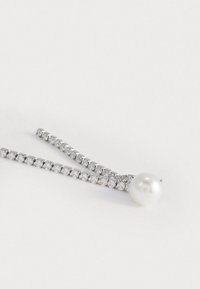 Καρφίτσα μαλλιών με στρας που διαθέτει ευθεία σχεδίαση, ασημένιο μέταλλο και μεγάλη λευκή πέρλα ως χαρακτηριστικό σε μία άκρη.