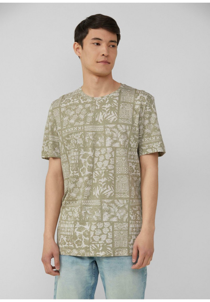 Groen T-shirt met korte mouwen, versierd met een wit botanisch patroon, ronde halslijn en een ontspannen pasvorm, gecombineerd met lichtblauwe jeans.